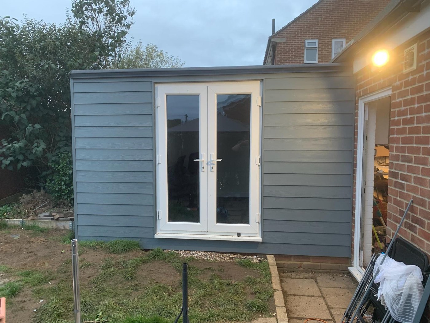 An insulated garden studio in grey weatherboard cladding with white French doors — MHP Building Contractors' own work
